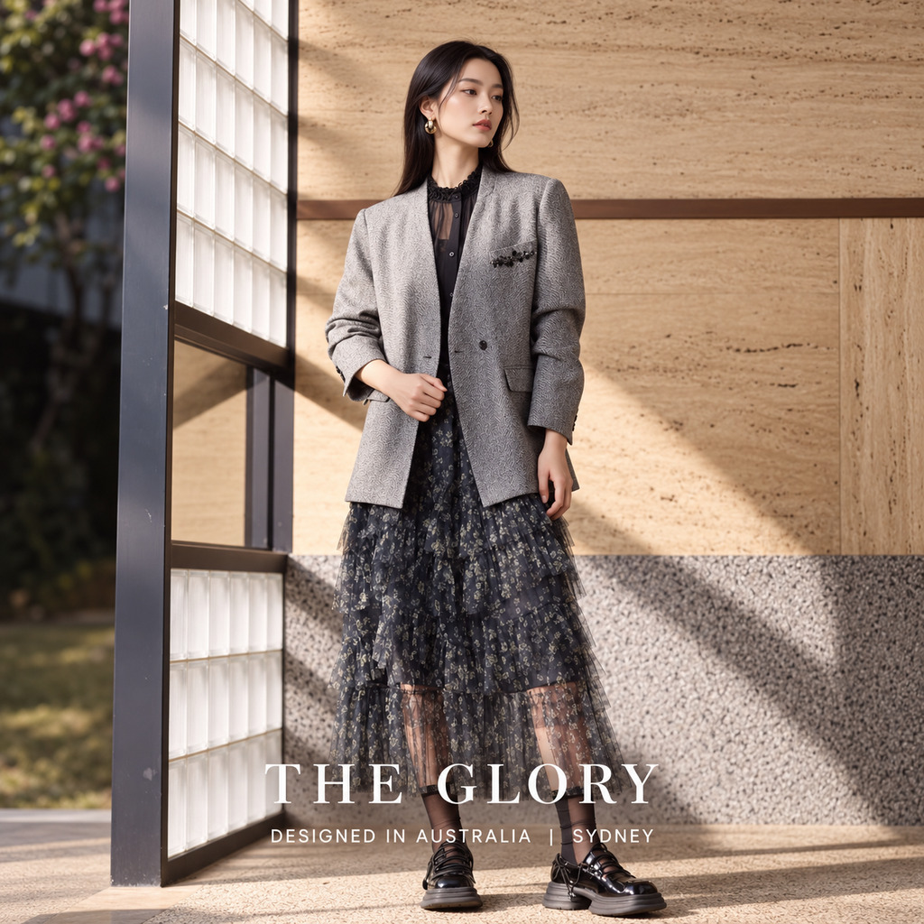 Model wearing a grey V-neck blazer over a black blouse and patterned skirt.