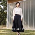 Model wearing a pale apricot long-sleeve silk blouse styled with a dark flowing skirt.