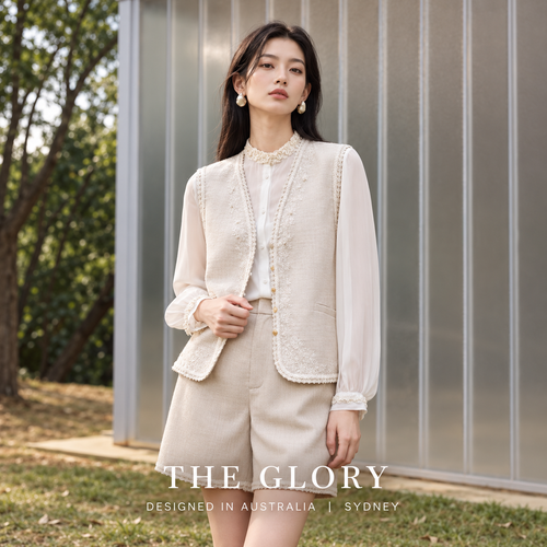Model wearing pale apricot shorts styled with a coordinating vest and white blouse.